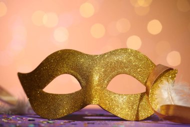 Renkli arka planda güzel bir karnaval maskesi, kurdeleler ve konfeti, bulanık ışıklar, yakın plan