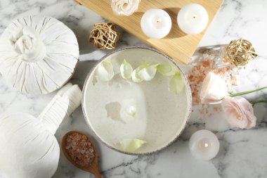Beyaz mermer masada bir kase su ve yanan mumlar ile spa kompozisyonu, düz yatıyordu.