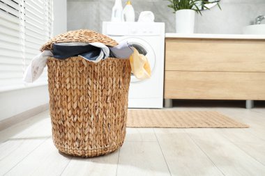 Banyoda yerde çamaşır dolu bir sepet.