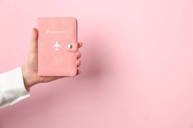 Pembe arka planda pasaportu olan bir kadın, yakın plan. Metin için boşluk