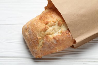 Beyaz ahşap masanın üstünde taze ekmek torbası, üst manzara.