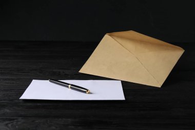 Siyah ahşap masa üzerinde mektup ve kalemle Kraft kağıt zarfı. Tasarım için model