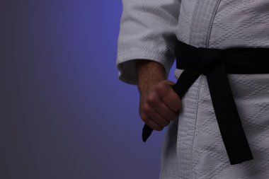 Koyu mor arka planda üniformalı karate dövüşçüsü, yakın plan. Metin için boşluk