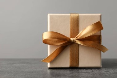 Gri masadaki fiyonklu hediye kutusu. Metin için boşluk