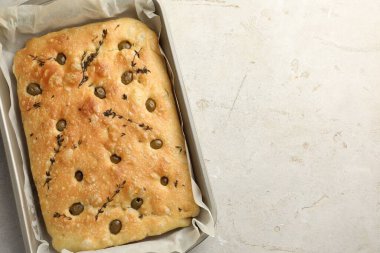 Zeytinli ve kekikli enfes Focaccia ekmeği açık gri masada, üst manzara. Metin için boşluk