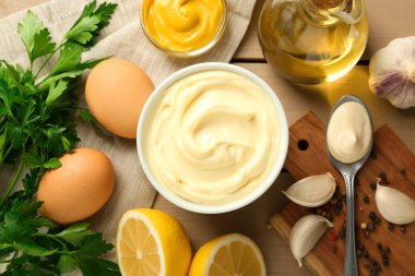 Lezzetli mayonez sosu kasede ve malzemeler ahşap masada, düz yerde.