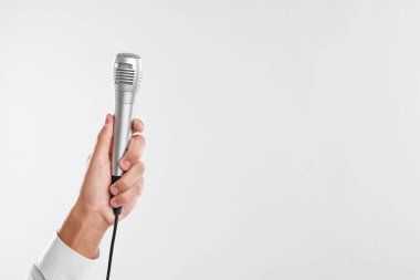 Açık gri arka planda mikrofonu olan adam, yakın plan. Metin için boşluk