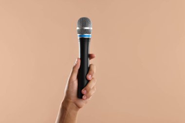 Bej arka planda mikrofonu olan adam, yakın plan.