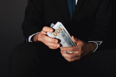 Yozlaşma konsepti. Siyah arkaplanda dolar banknotları tutan adam, yakın plan.