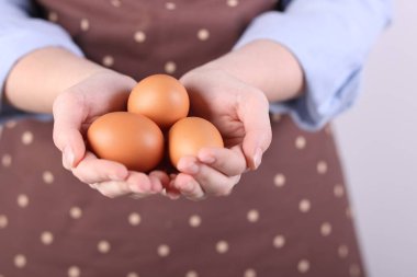 Hafif arka planda çiğ yumurtası olan kadın, yakın plan.