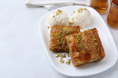 Beyaz fayanslı masada ezilmiş fındıklı ve dondurmalı enfes baklava, yakın plan. Metin için boşluk