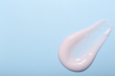 Açık mavi arka planda krema örneği, üst manzara. Metin için boşluk