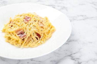 Pastırmalı Carbonara makarnası beyaz mermer masada, yakın plan.