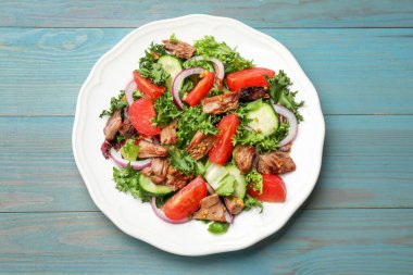 Açık mavi ahşap masada nefis taze ton balığı salatası.