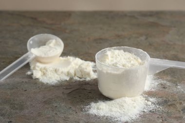 Gri desenli masadaki protein tozu ve kepçeler