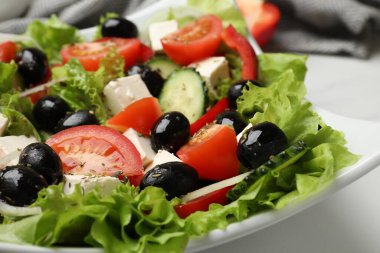 Lezzetli taze Yunan salatası beyaz masada, yakın plan.