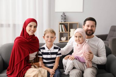 Mutlu Müslüman aile evdeki kanepede oturuyor.