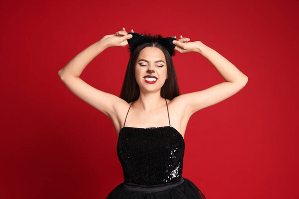 Beautiful woman with cat makeup and ears on red background