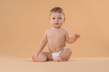 Bej arka planda oturan bezli şirin bir bebek.