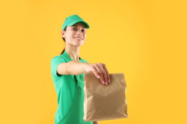 Turuncu arka planda kese kağıdı olan fast food işçisi, seçici odaklı.