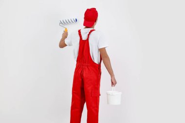 Erkek tamirci duvarları boyuyor, içeride patenli, arka manzaralı.