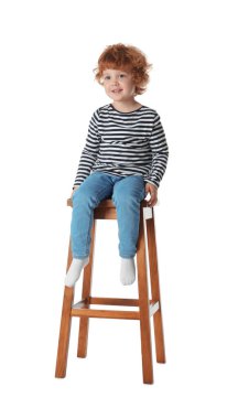 Küçük çocuk beyaz arka planda taburede oturuyor.