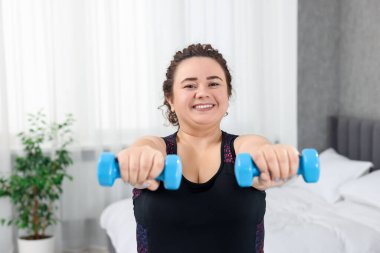 Artı evde dambıl eğitimi alan bir kadın.