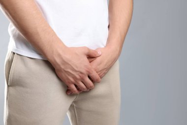 Cinsel yolla bulaşan hastalıklar. Gri arka planda semptomlardan muzdarip bir adam, yakın plan