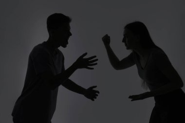 Aile içi şiddet. Gri arka planda tartışan çiftlerin silueti