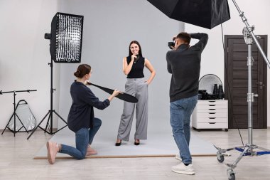 Profesyonel fotoğraf stüdyosunda modelle çalışan fotoğrafçı ve asistan.