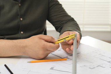 Projeyle çalışan mimar, yakın plan. Masada farklı teknik çizimler var.