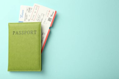 Passport with tickets on light blue background, top view. Space for text