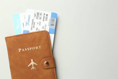 Kahverengi kapaklı pasaport ve açık gri arka planda uçuş biletleri, üst manzara. Metin için boşluk