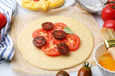 Domates ve fesleğenli çiğ galetler beyaz fayanslı masada, yakın plan.