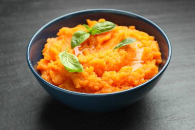 Tatlı patates püresi ve fesleğen. Koyu gri desenli masa, yakın plan.