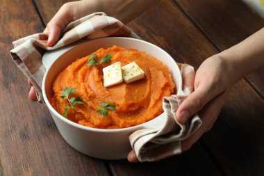 Ahşap masada bir kase lezzetli patates püresi olan kadın, yakın plan.