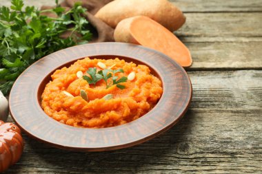 Lezzetli patates püresi, kabak tohumları, taze sebzeler ve ahşap masada maydanoz, yakın plan.