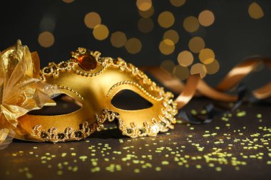 Güzel bir karnaval maskesi ve koyu arkaplanda bulanık ışıkları olan konfeti, yakın plan.