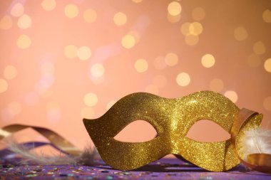 Renkli arka planda güzel bir karnaval maskesi, kurdeleler ve konfeti, bulanık ışıklar, yakın plan