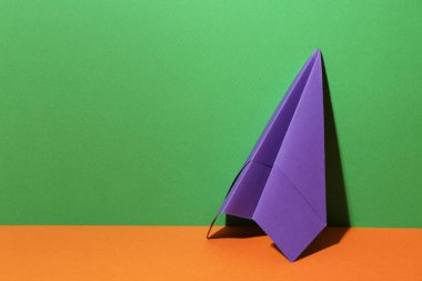 Renkli arka planda el yapımı mor kağıt uçak. Metin için boşluk