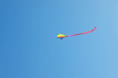 Mavi gökyüzünde uçan renkli bir uçurtma