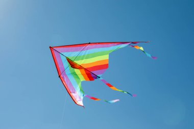 Mavi gökyüzünde uçan renkli bir uçurtma