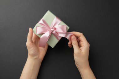 Kadın hediye kutusunu siyah arkaplanda açıyor, üst görünümde