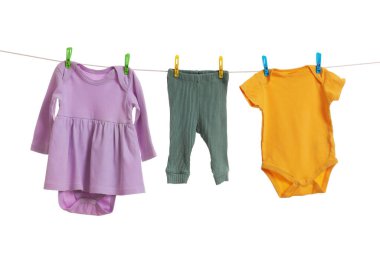 Different baby clothes drying on laundry line against white background