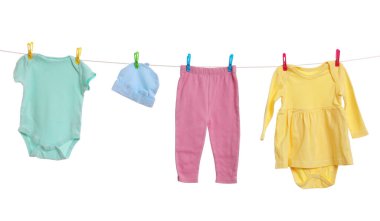 Different baby clothes drying on laundry line against white background