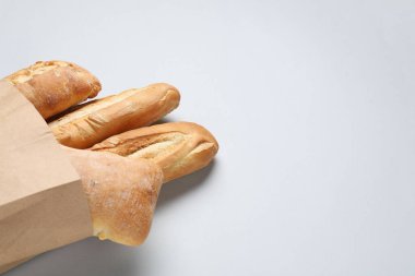 Beyaz arka planda taze baget ve ciabatta içeren kağıt torba. Metin için boşluk