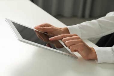 Beyaz masada tablet kullanan bir iş kadını, yakın plan. Modern teknoloji