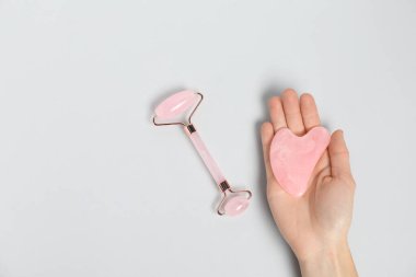 Gua sha aletli ve arka planda yüz silindiri olan bir kadın. Metin için boşluk