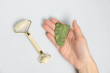 Gua sha aracı ve arka planda yüz silindiri olan kadın, üst görünüm