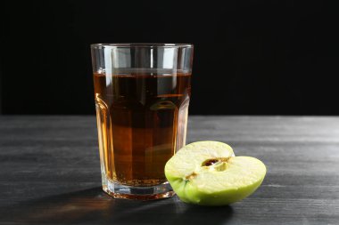 Bardakta taze meyve suyu ve siyah ahşap masada yarım meyve suyu.